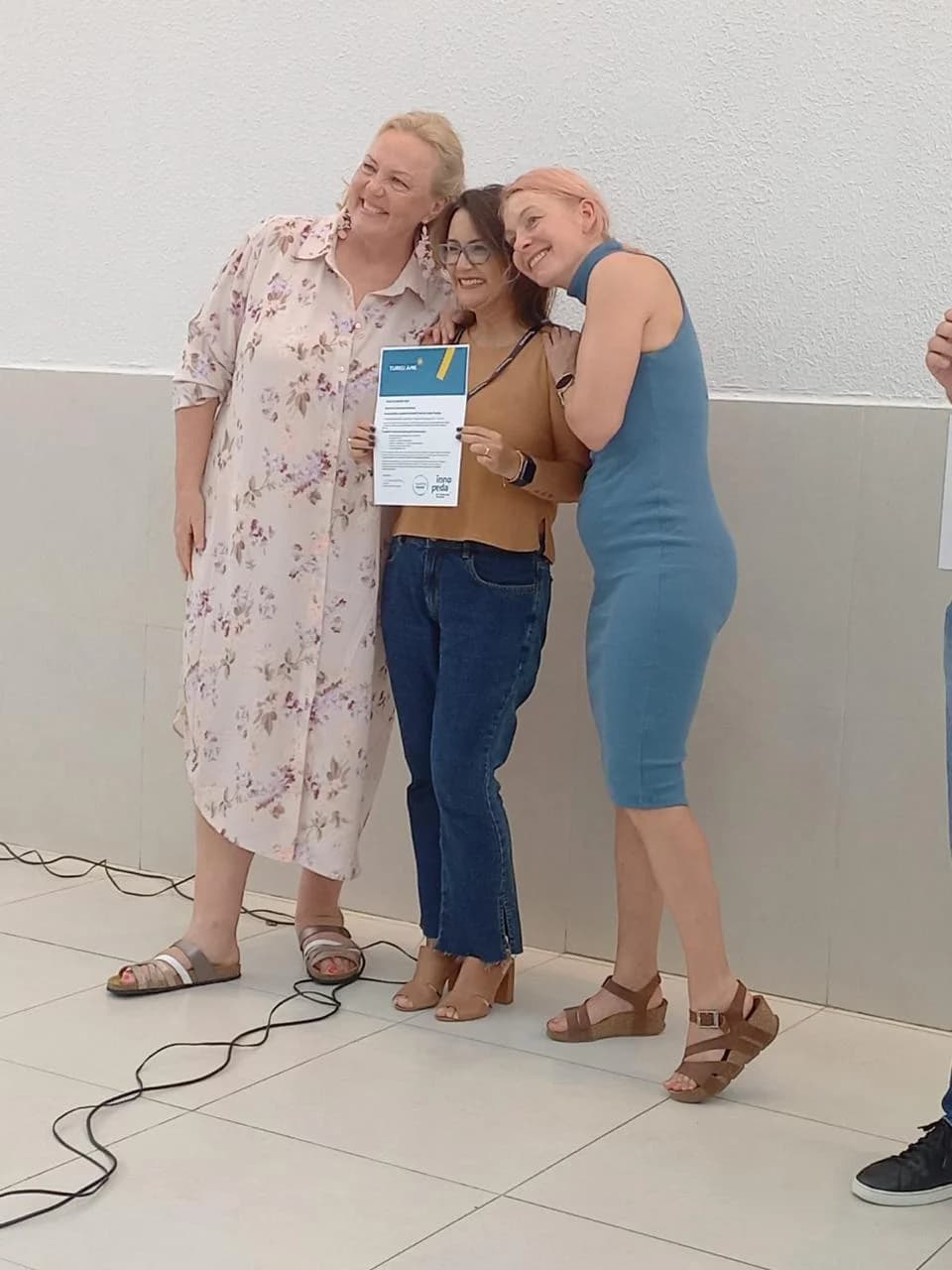 Professora recebendo o certificado InnoPeda junto às educadoras finlandesas da AMD Turku