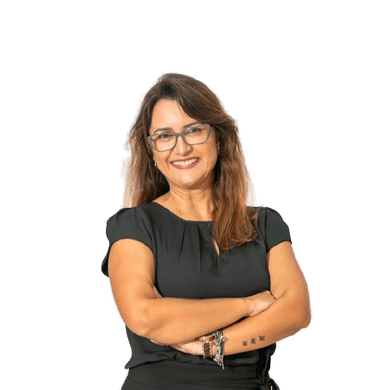 Elizandra Barbosa, professora do Ensino Fundamental I, sorrindo com braços cruzados em pose profissional e acolhedora